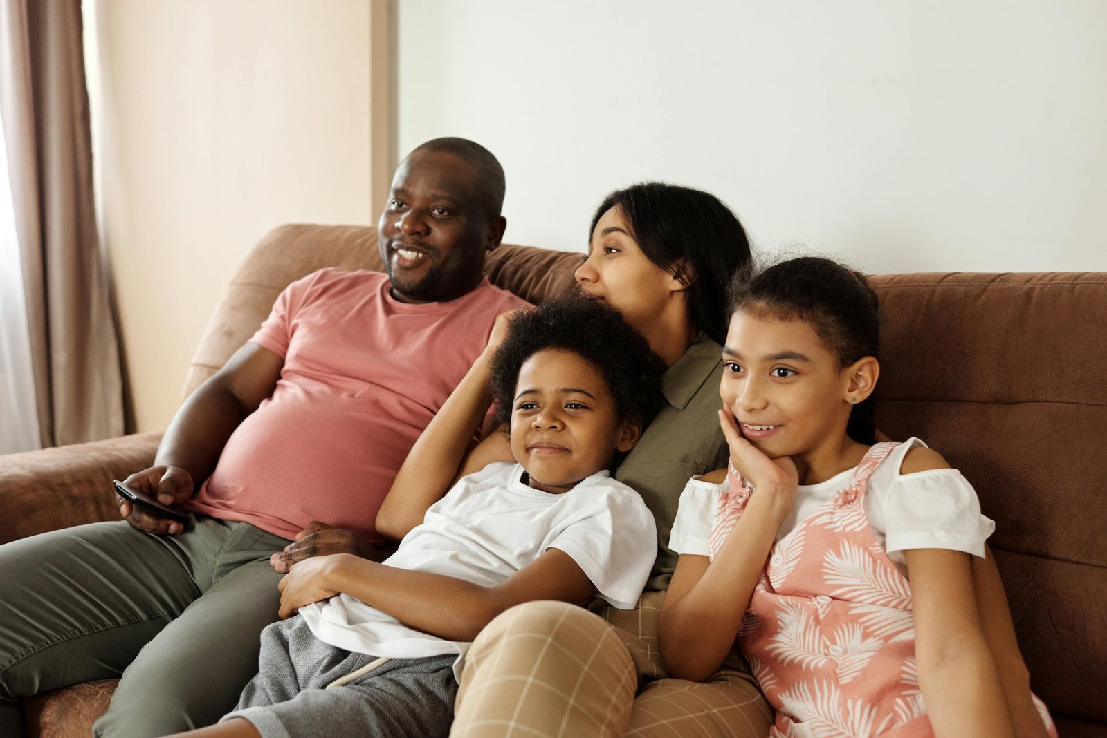A joyful family of four enjoying time together on a comfy sofa indoors.